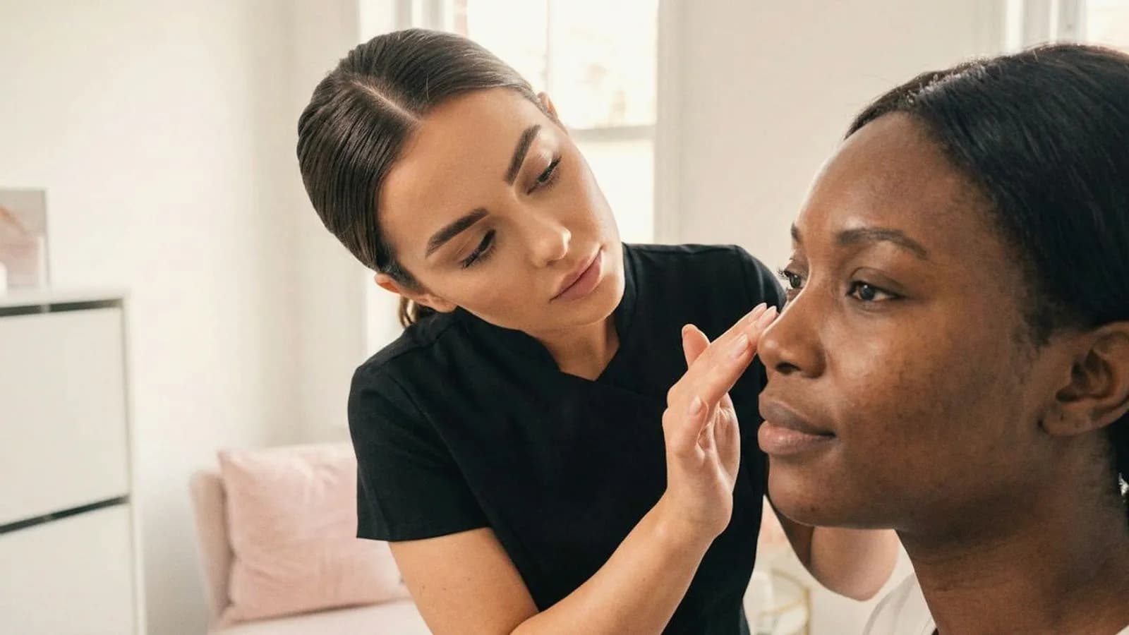 A practitioner looks closely at a client's skin in natural light.